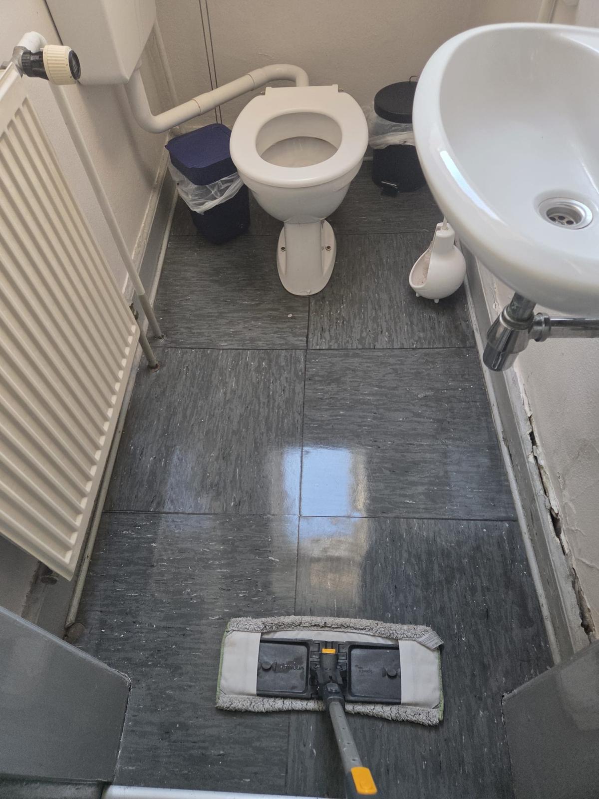 Sanitärraum mit WC und Waschbecken während der Bodenreinigung